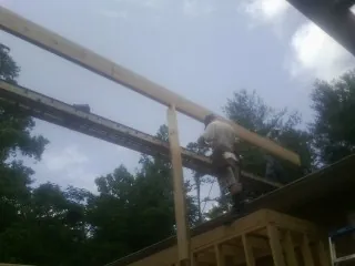 Carpenter setting a ridge beam over a new addition frame — Ice Dam Removal by Roofing Brothers in Barco