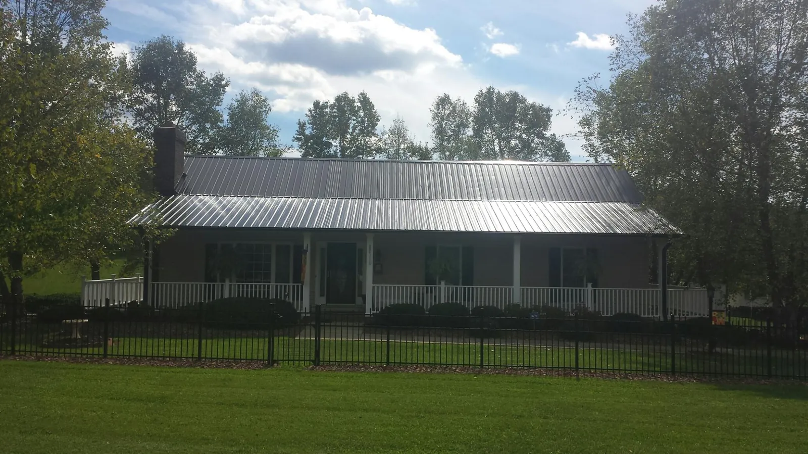Gray metal roof on a brick ranch with a full width front porch — Gutter Guard Installation work by our crew in Barco