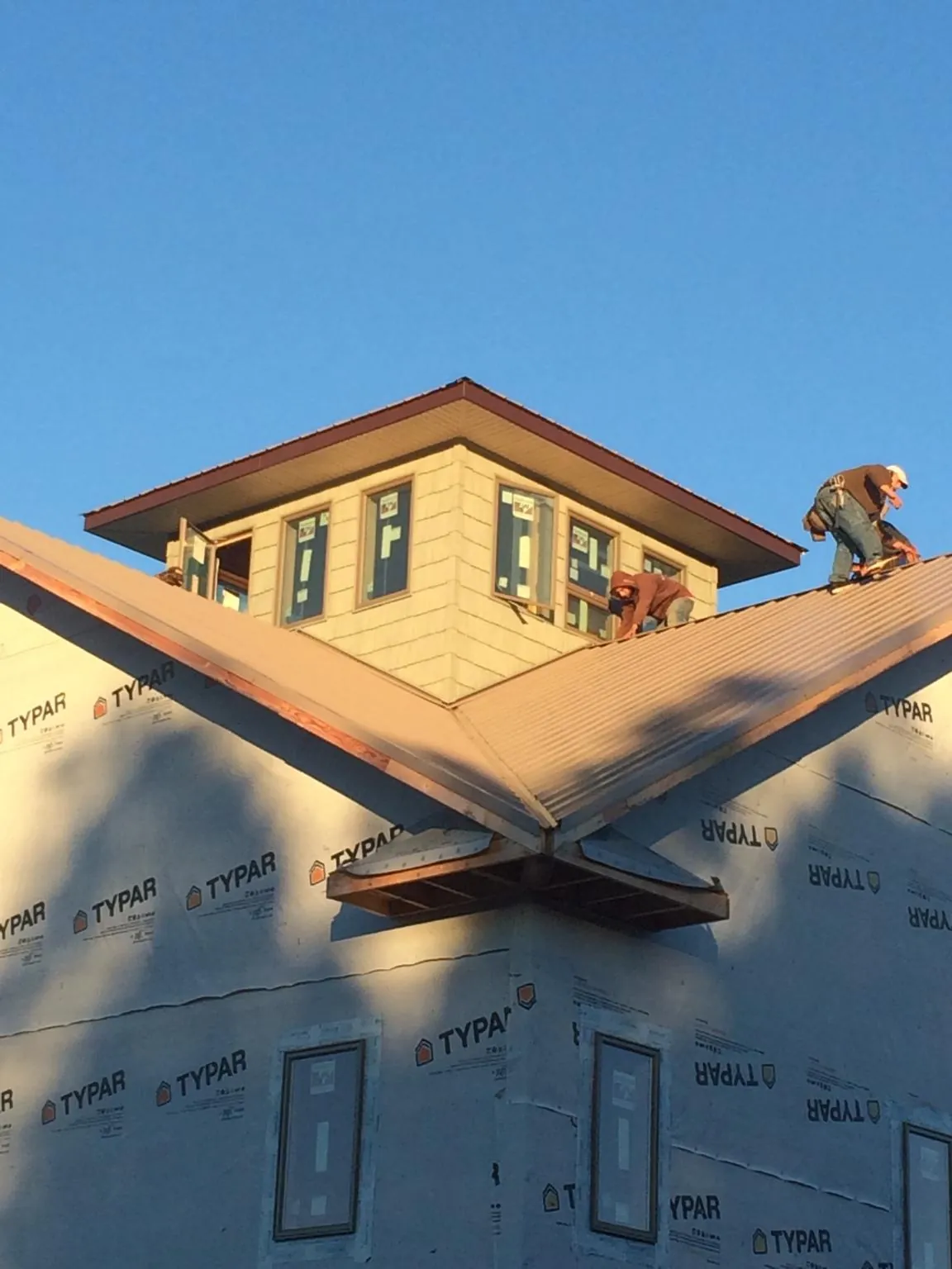 Roofers working around a rooftop cupola on a new metal roof at sunset — Roof Waterproofing in Barco by Roofing Brothers